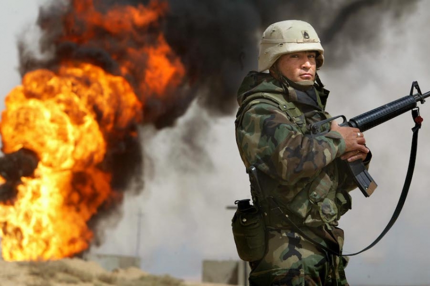 A U.S. soldier stands guard in March of 2003 next to an oil well at the Rumayla oil fields set ablaze by retreating Iraqi troops. (Photo by Mario Tama/Getty Images)